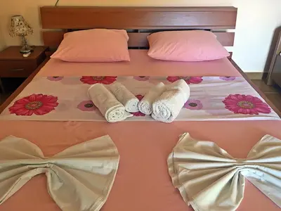 a bed with two beds with towels and pink pillows at Apartments Pelinkovic in Ulcinj