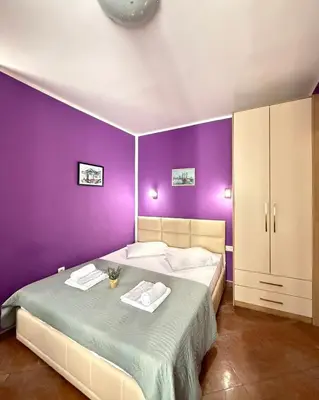 a purple bedroom with a bed with two towels on it at Apartments Casa del Sol Jovana in Kotor