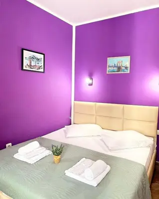 a purple bedroom with a bed with towels on it at Apartments Casa del Sol Jovana in Kotor