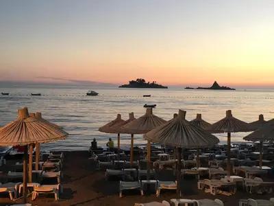 a beach with chairs and umbrellas at sunset at Villa Julia in Petrovac na Moru