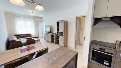 a kitchen and living room with a table and a couch at Piano Apartments Delta City in Podgorica