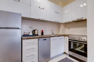 a white kitchen with white cabinets and a sink at Piano Apartments Delta City in Podgorica