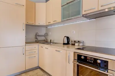 a kitchen with white cabinets and a stove top oven at Piano Apartments Delta City in Podgorica