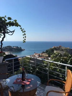 a table with wine glasses on a balcony with the ocean at Apartment Jana in Ulcinj