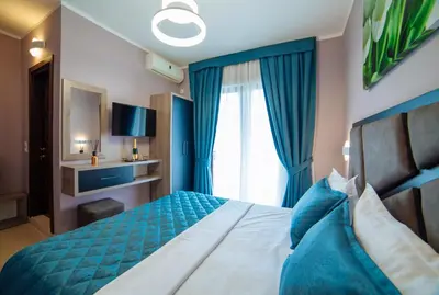 a bedroom with a large bed with blue curtains at Hotel Princess & Spa in Ulcinj