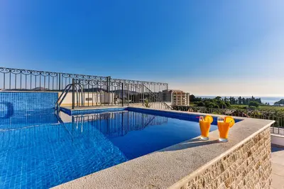 a swimming pool with two orange glasses next to it at De Lux Apartments Luka in Bar