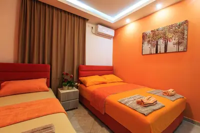 two beds in a room with orange walls at De Lux Apartments Luka in Bar