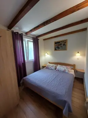 a bedroom with a bed with purple curtains and a window at Garden apartmant near sea in Kotor
