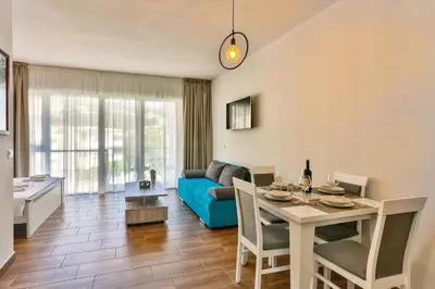 a living room with a table and a blue couch at Luna Apartmani in Sutomore