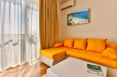 a living room with an orange couch and a window at Luna Apartmani in Sutomore