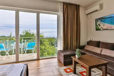 a living room with a couch and a large window at Luna Apartmani in Sutomore