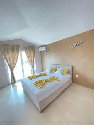 a bedroom with a large white bed with yellow pillows at Apartments Harris in Ulcinj