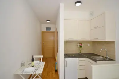 a kitchen with white cabinets and a sink and a table at Apartments Posto Capitano 0202 in Kotor