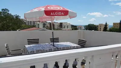 a table on a balcony with an umbrella at Guesthouse Ada in Bar