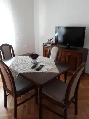 a dining room table with chairs and a television at Apartment K2 in Radanovići