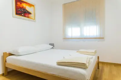 a white bedroom with a bed with a window at Apartment Blue Adriatic in Budva
