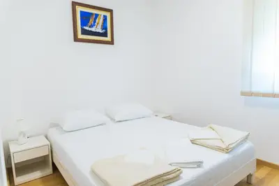 a white bedroom with a bed and a picture on the wall at Apartment Blue Adriatic in Budva