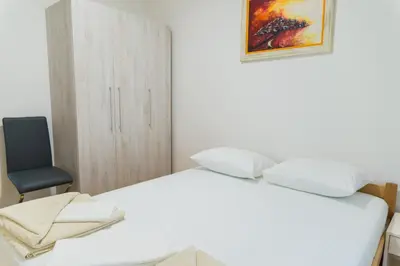a bedroom with a white bed and a chair at Apartment Blue Adriatic in Budva