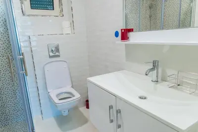a white bathroom with a toilet and a sink at Apartment Blue Adriatic in Budva