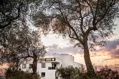 a white building with trees in front of it at Hotel Ulliri & SPA in Ulcinj