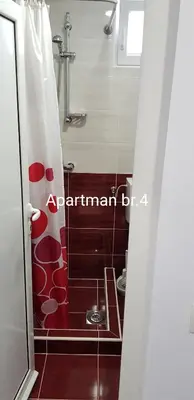 a bathroom with a shower with a red and white shower curtain at Apartmani Nikmil Bar- Šusanj in Bar