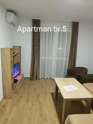 a living room with a table and a tv at Apartmani Nikmil Bar- Šusanj in Bar
