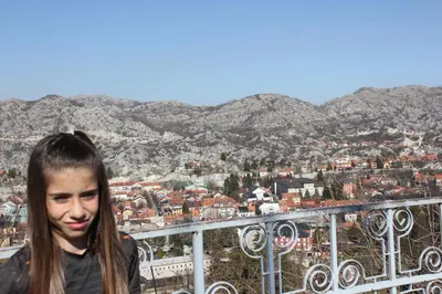 a girl standing on a balcony with a view of a city at Apartments Kapisoda in Cetinje