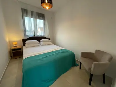 a small bedroom with a bed and a chair at OSA Holiday in Ulcinj