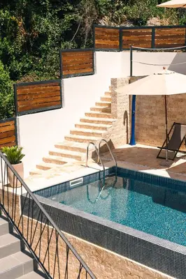 a swimming pool with stairs and an umbrella at Casa Bianca & Spa in Ulcinj
