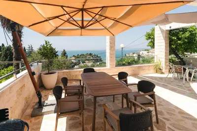 a table and chairs under an umbrella on a balcony at Casa Bianca & Spa in Ulcinj