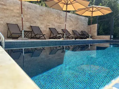 a swimming pool with chairs and umbrellas next to it at Casa Bianca & Spa in Ulcinj