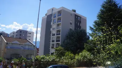 a tall white building with trees in front of it at Apartments LORA Bokeljske brigade in Budva