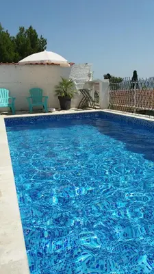 a large blue swimming pool with two chairs and an umbrella at Apartment Tijana in Bar