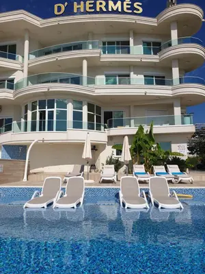 a hotel with chairs and umbrellas next to a swimming pool at Apartments D'Hermes in Ulcinj