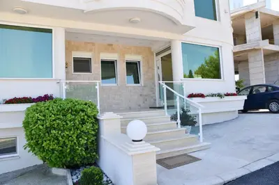 a house with stairs and a car parked in front of it at Apartments D'Hermes in Ulcinj