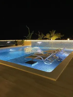 a swimming pool at night with a lit up at Apartments D'Hermes in Ulcinj