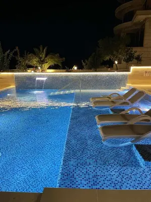 a swimming pool at night with lounge chairs in it at Apartments D'Hermes in Ulcinj