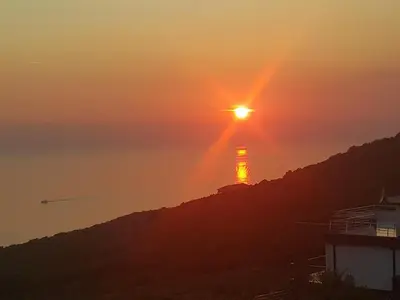 a sunset over the ocean with the sun setting on a hill at Apartment Vila Mirela in Krimovice
