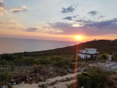 a sunset over the ocean with a house on a hill at Apartment Vila Mirela in Krimovice