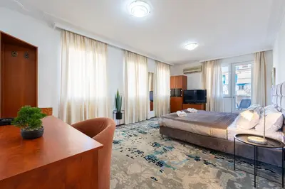 a bedroom with a bed and a table and a couch at Hotel Bojatours in Podgorica