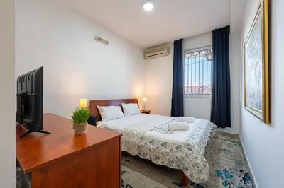 a bedroom with a bed and a desk and a television at Hotel Bojatours in Podgorica