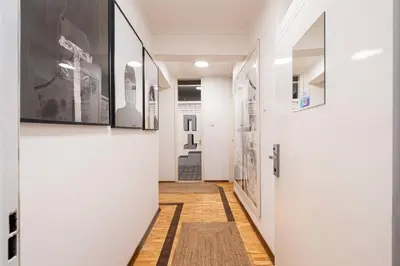 a hallway with white walls and a door with a rug at Hotel Bojatours in Podgorica