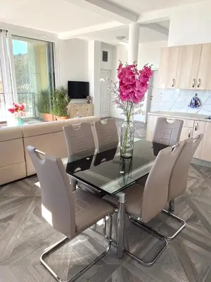 a dining room table with chairs and a vase of pink flowers at Villa Casanego in Sutomore