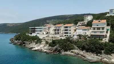 a group of houses on a hill next to the water at ViLena Apartmani in Tivat
