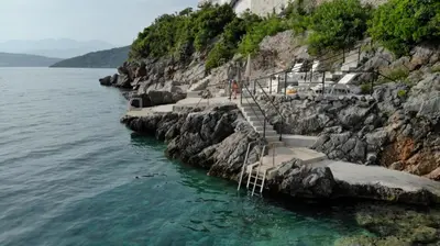 a group of stairs on a cliff next to the water at ViLena Apartmani in Tivat