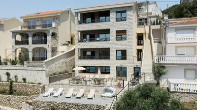 an apartment building with lounge chairs in front of it at ViLena Apartmani in Tivat