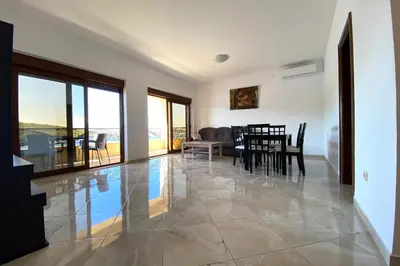 a dining room and living room with a table and chairs at ViLena Apartmani in Tivat