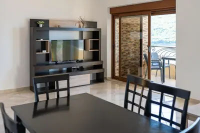 a dining room with a table and chairs and a television at ViLena Apartmani in Tivat