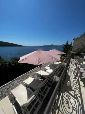 a group of chairs and an umbrella on a balcony at ViLena Apartmani in Tivat