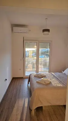 a bedroom with a large bed and two windows at Apartments Radoman in Ulcinj